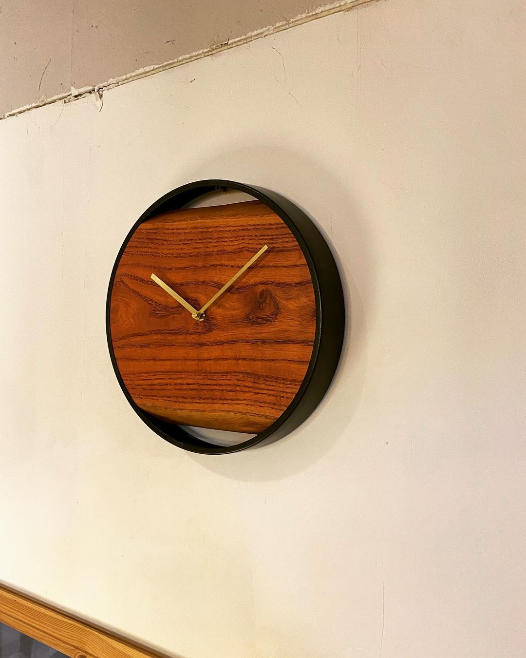 A minimalist wooden wall clock with gold hands