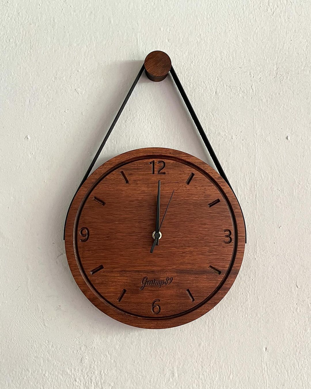 A minimalist wooden wall clock with triangular suspension