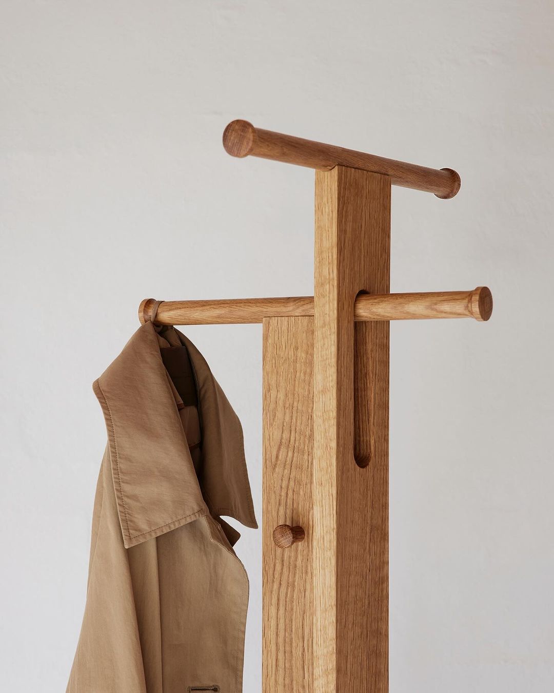 A coat hanging on a minimalistic wooden coat stand