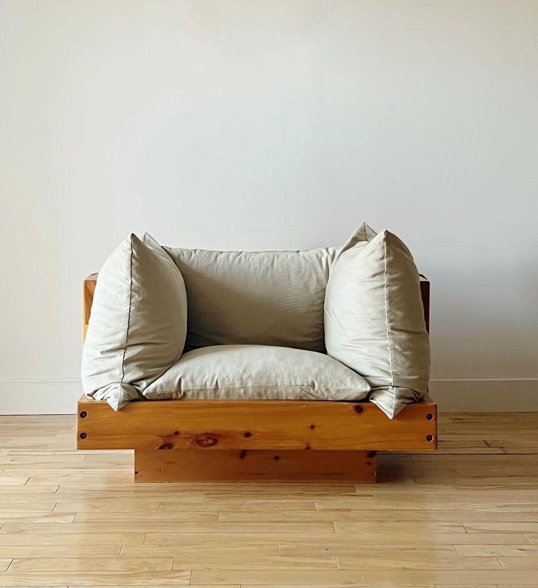 A minimalistic wooden couch with beige cushions