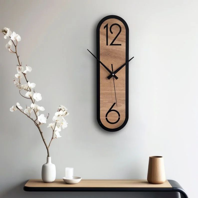 Minimalistic wooden wall clock on a grey wall with vase and white flowers on a shelf