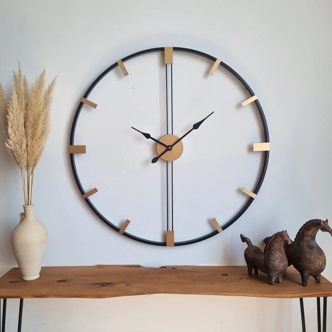 A minimalist wall clock with wooden hour marks on a black circular frame mounted above a wooden console table