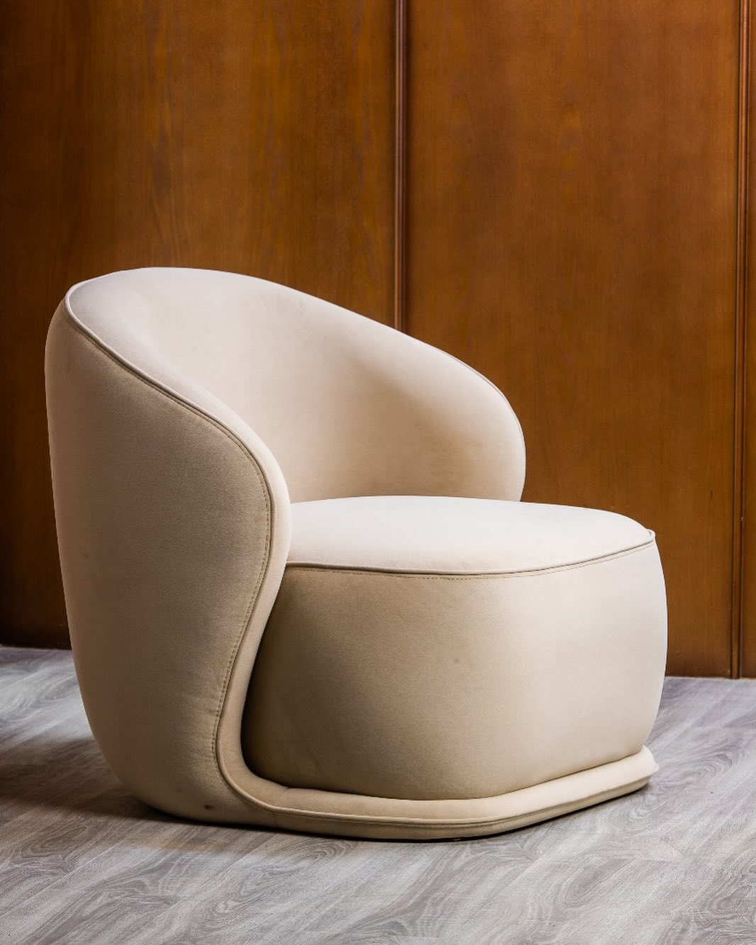 A minimalist modern chair with a smooth, curved design in a neutral tone