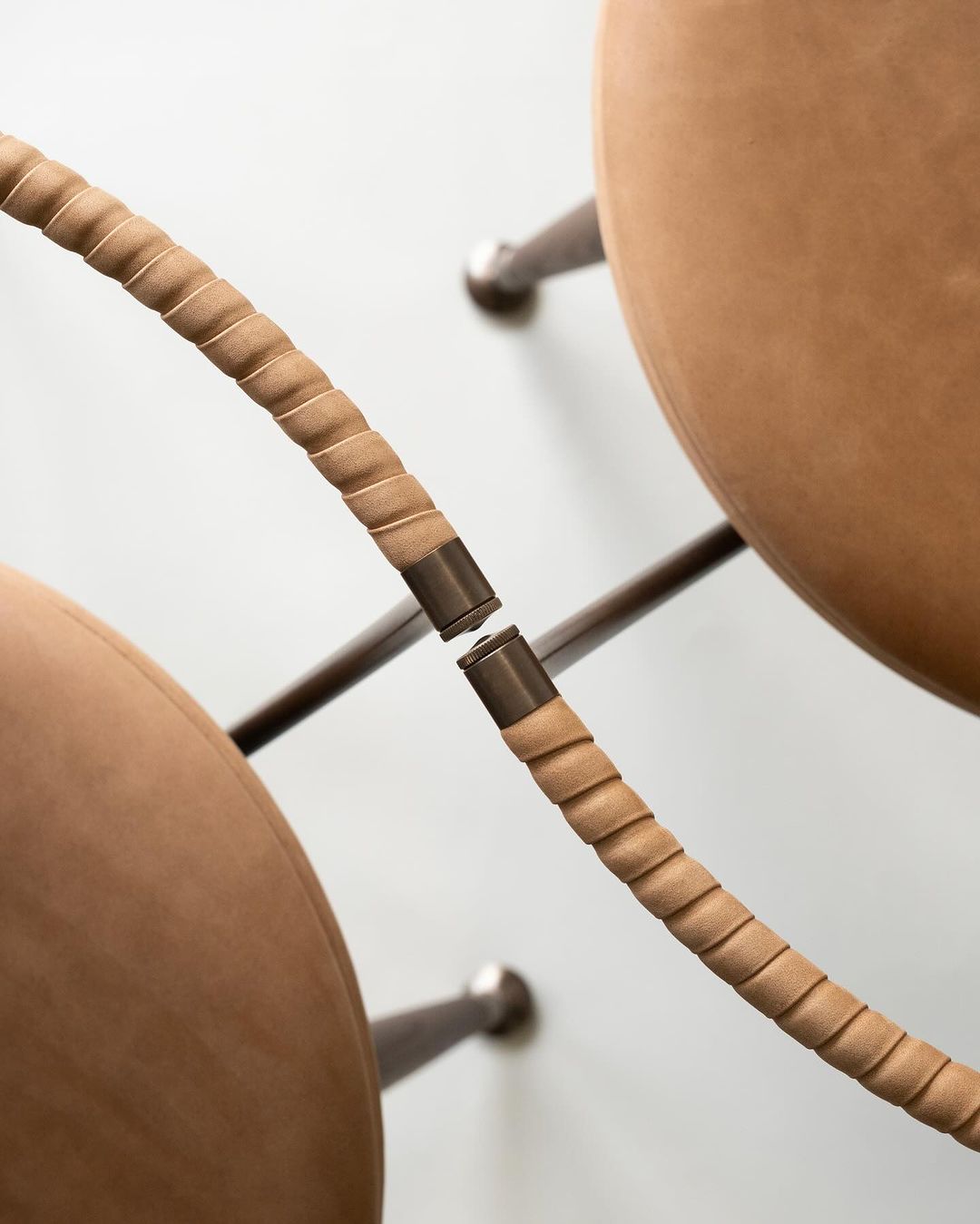 A close-up view of a modern chair showcasing its unique fabric-wrapped frame and tan leather cushions