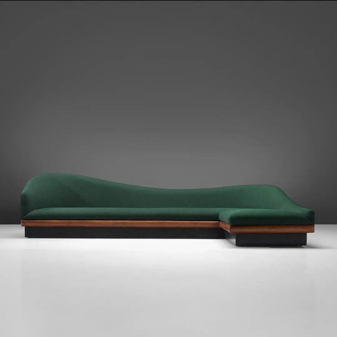 A modern green chaise longue with sleek wood accents