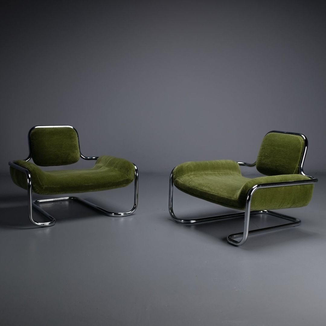 A pair of modern green velvet chairs with sleek chrome frames