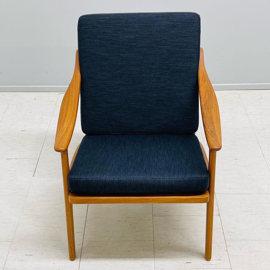 A minimalist modern chair with a sleek wood frame and dark blue upholstery