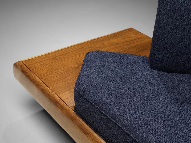 A modern minimalist chair with wooden base and dark blue upholstery