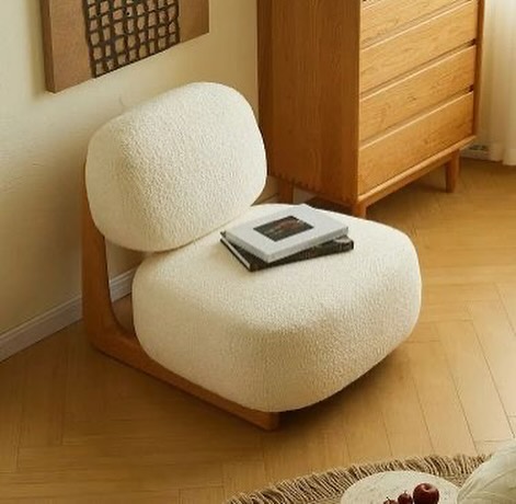 A modern and minimalist chair design featuring a curved wood frame and plush, textured cushions.