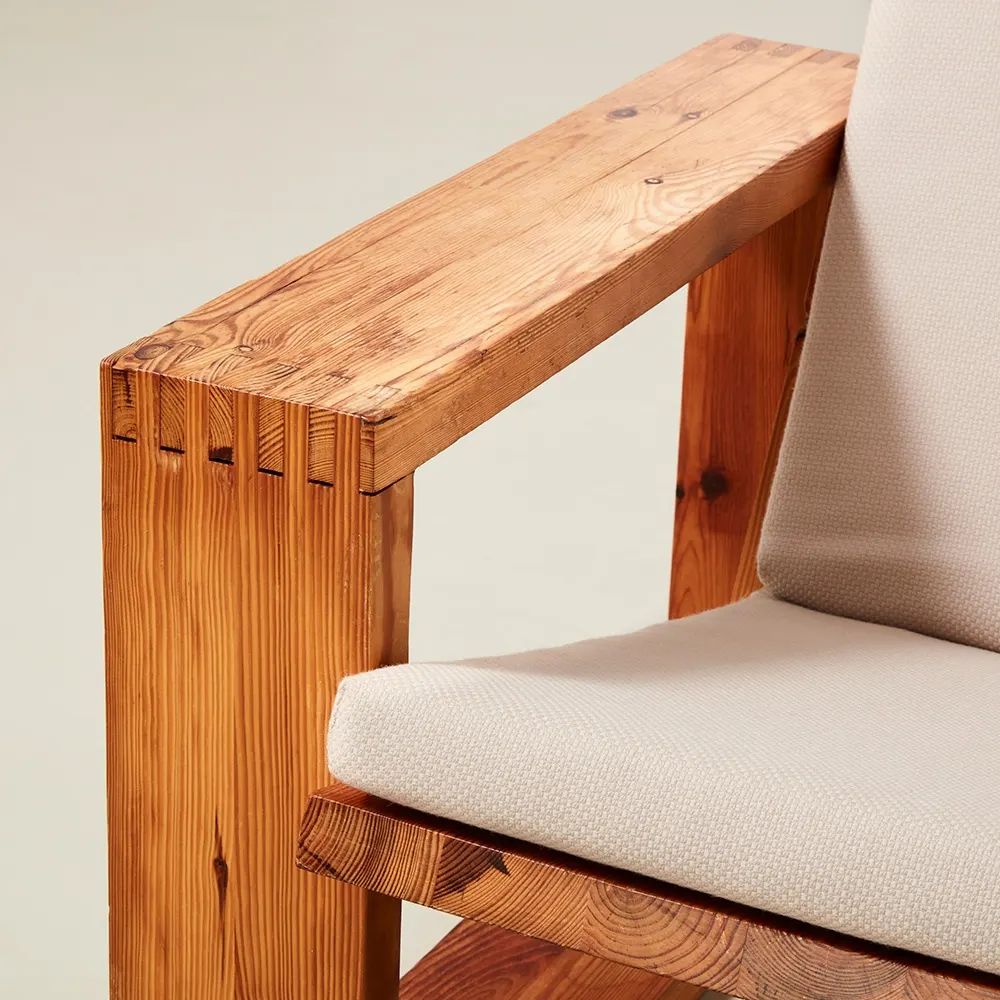 A minimalist chair with robust wooden armrests and a comfy beige cushion