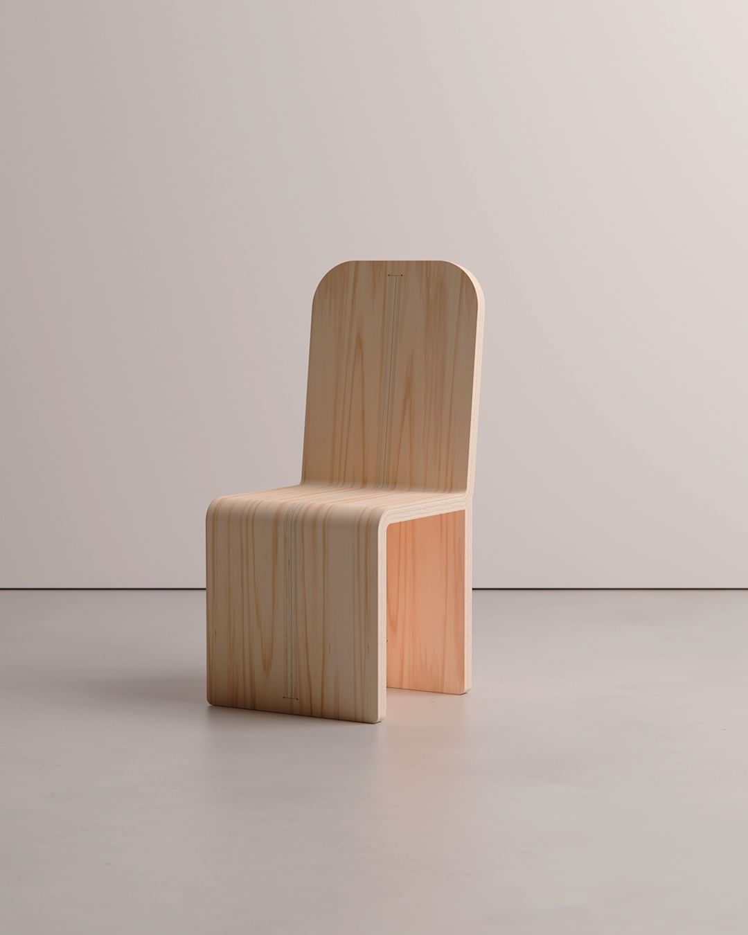 A minimalist wooden chair with a sleek, curved design