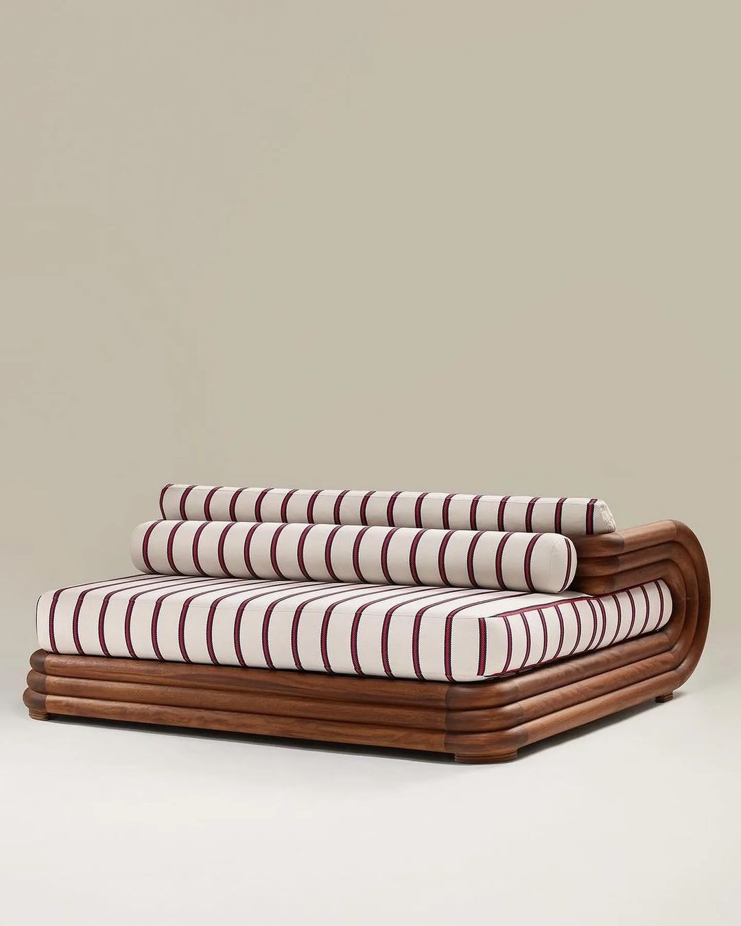 A uniquely designed modern sofa with striped cushions and a curved wooden frame