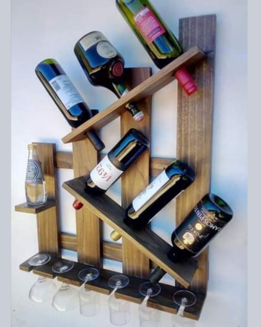 A contemporary wall-mounted wine rack with bottles and glasses