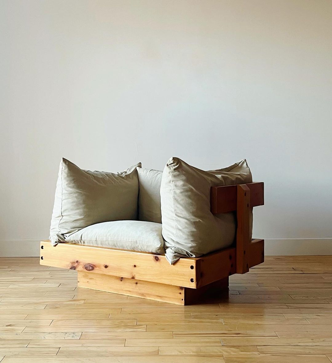 A rustic yet modern wooden armchair with plush cushions