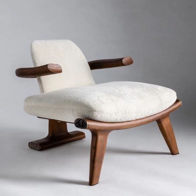 A unique wooden armchair with plush white upholstery