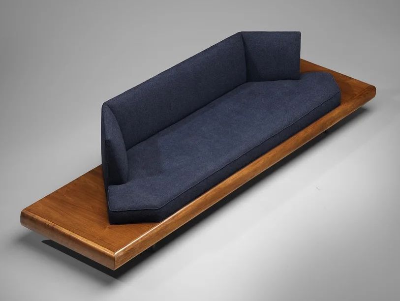 A sleek modern sofa with a low-profile wooden base and navy blue upholstery.