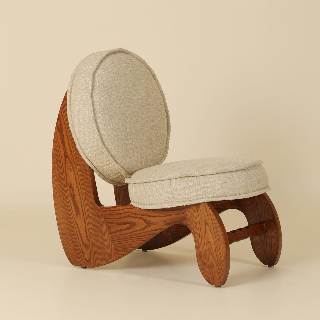 A uniquely crafted wooden chair with an ergonomic curved design and plush beige cushioning