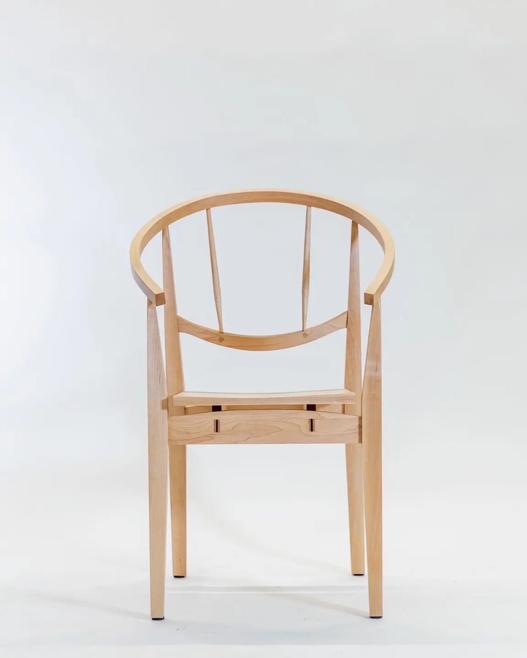 A wooden chair with an arched backrest and vertical slats on a white background