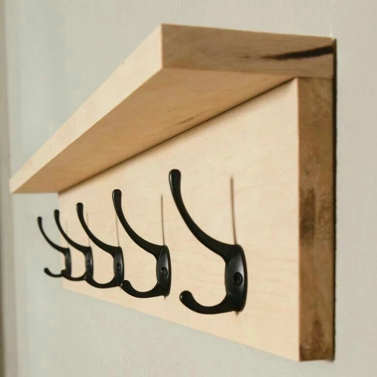 A modern wooden wall-mounted coat rack with black metal hooks