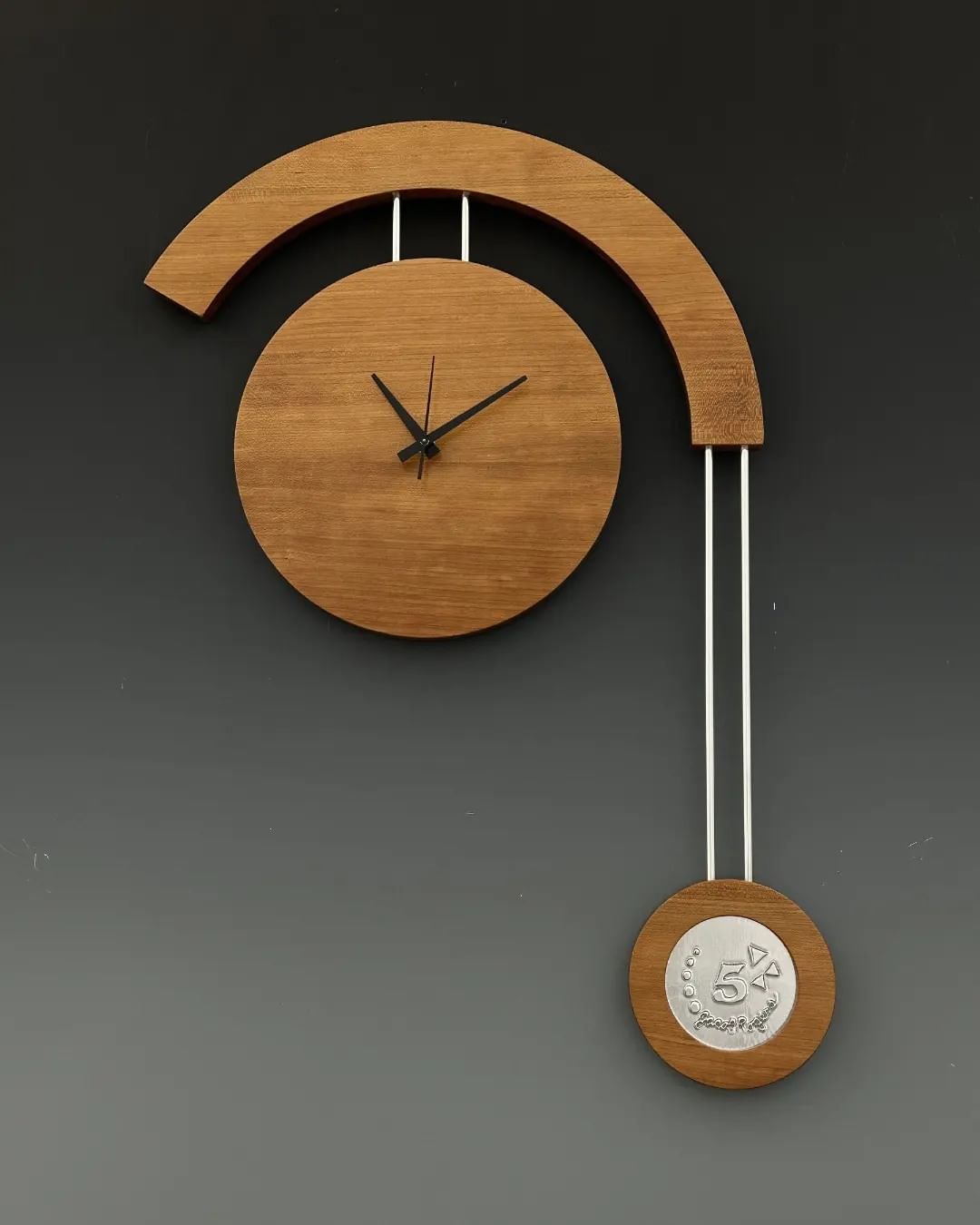 A modern wooden wall clock with an artistic pendulum design