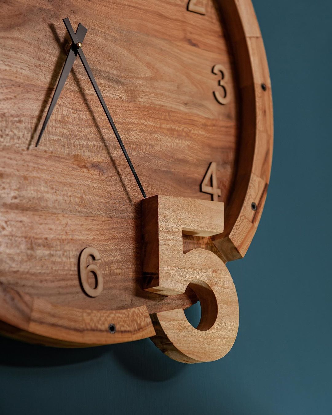 A contemporary wooden wall clock with numerals protruding from the surface