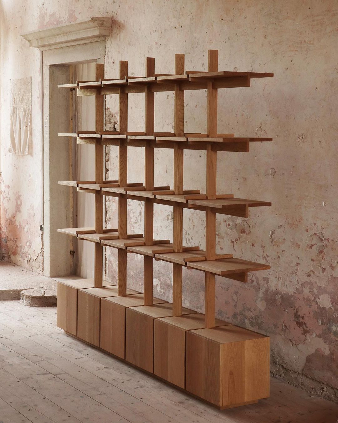 A minimalist and functional wooden shelving unit in a rustic room