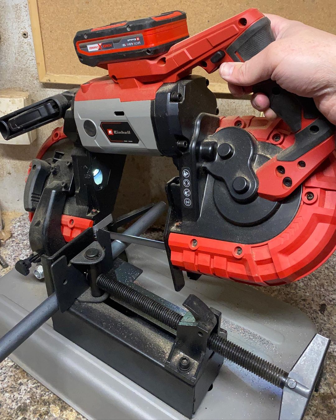 A person operating a powerful red and black Einhell metal cutting band saw