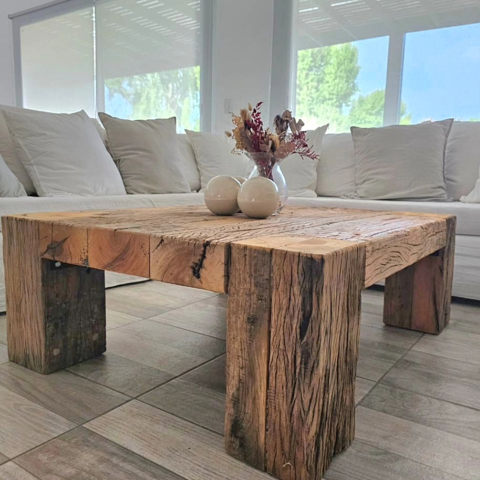 A robust coffee table crafted from thick slabs of reclaimed wood, exuding a rustic charm