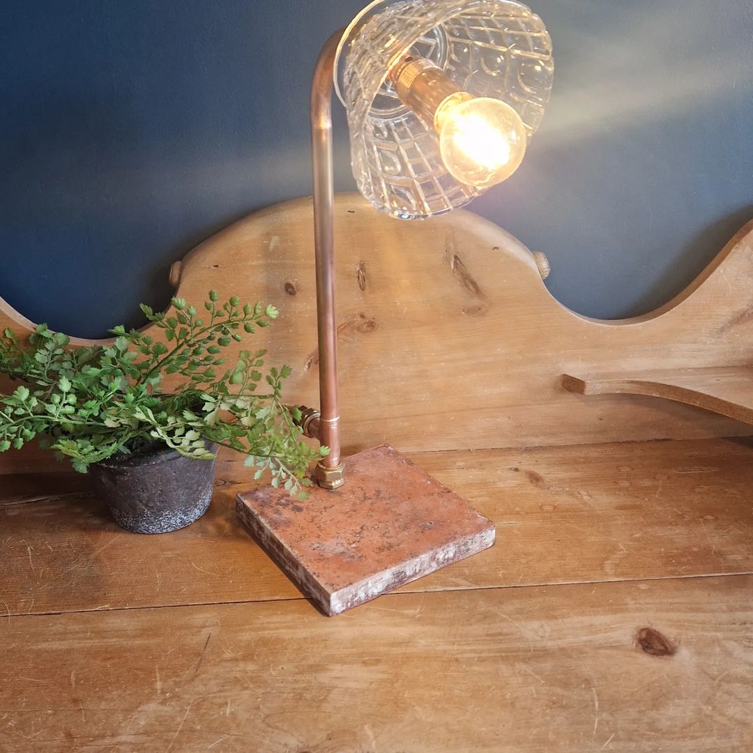 A rustic-style desk lamp with an exposed Edison bulb, set against a blue wall