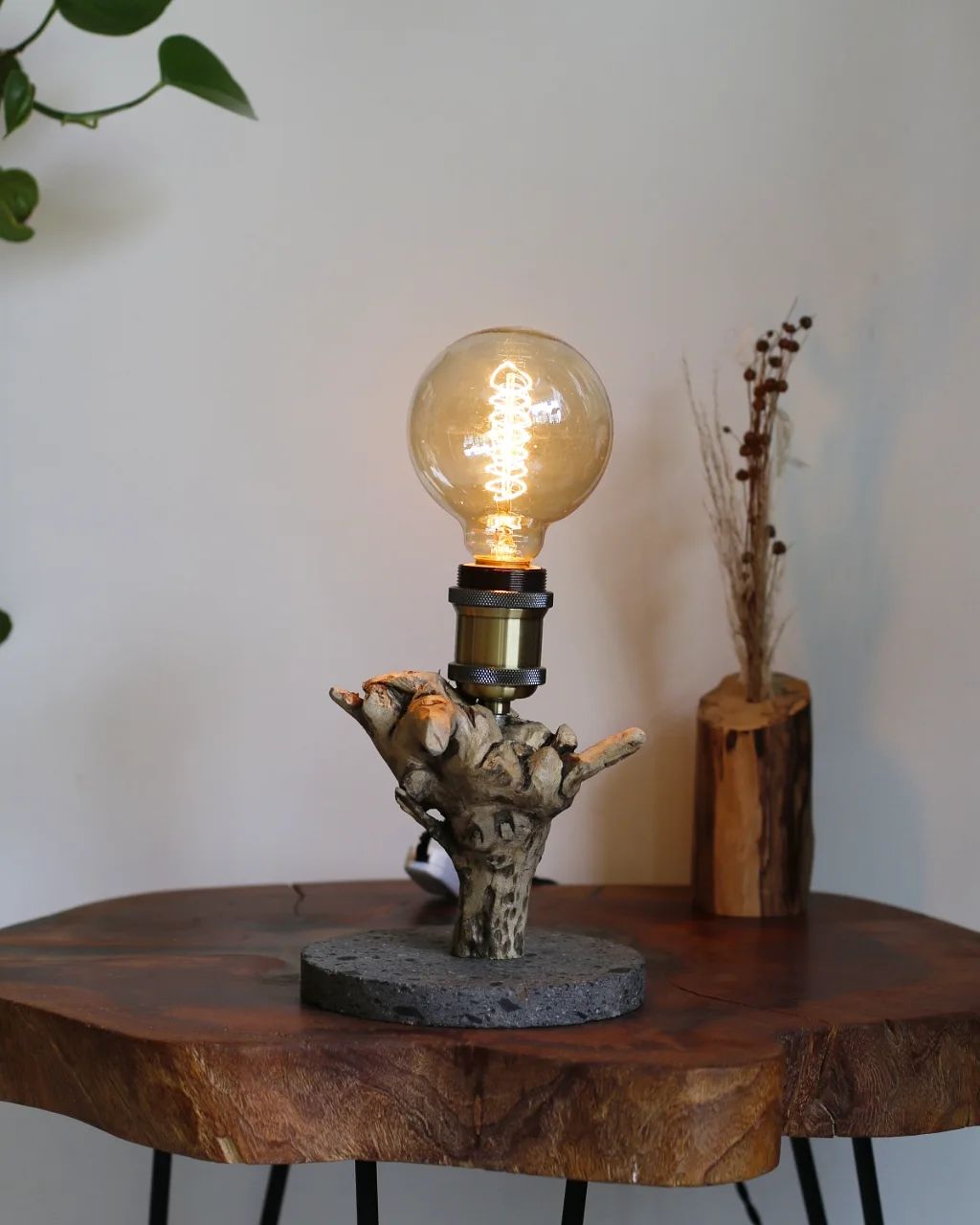 A unique table lamp with a rustic driftwood base and an illuminated filament bulb