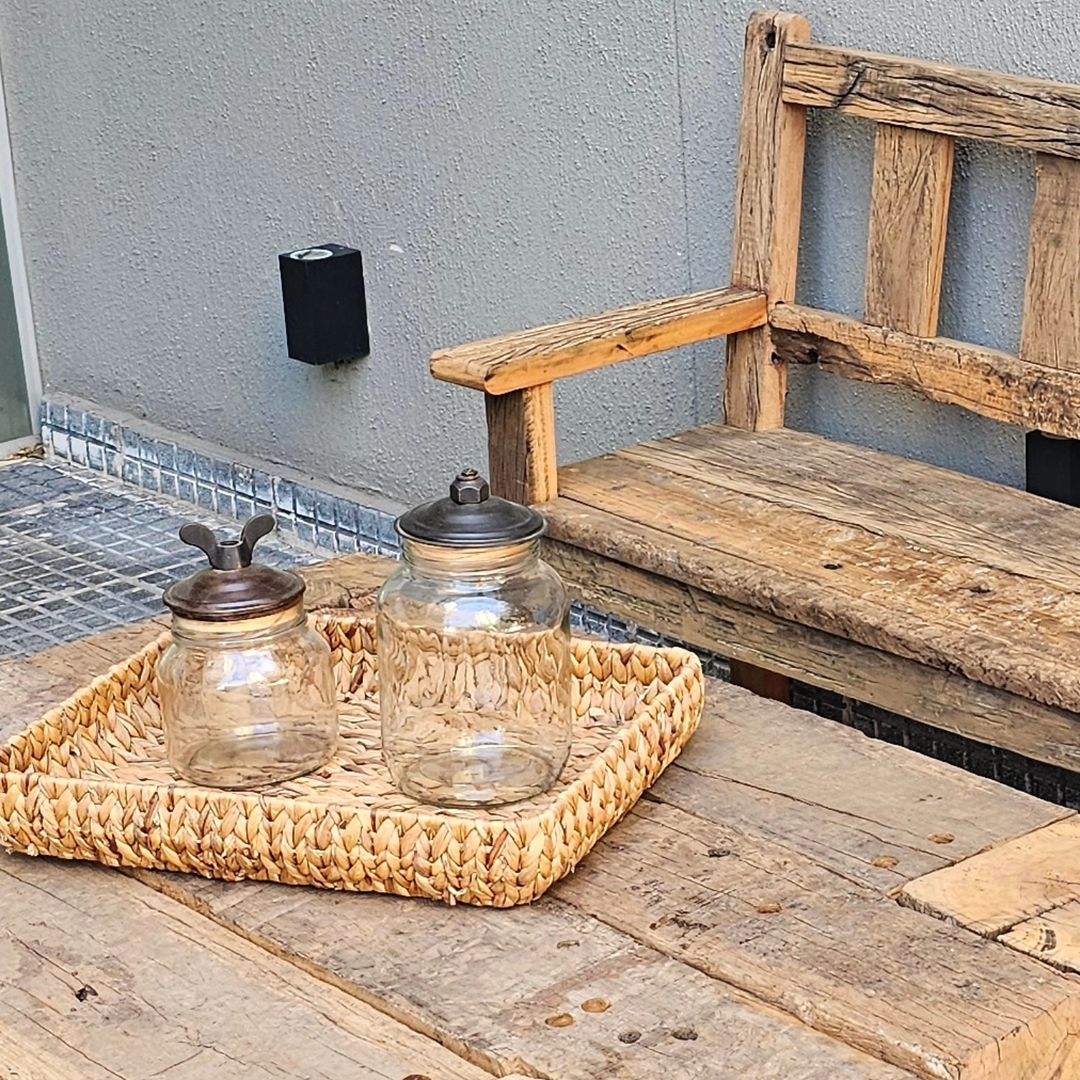 Rustic outdoor seating arrangement with a wooden bench and glass jars