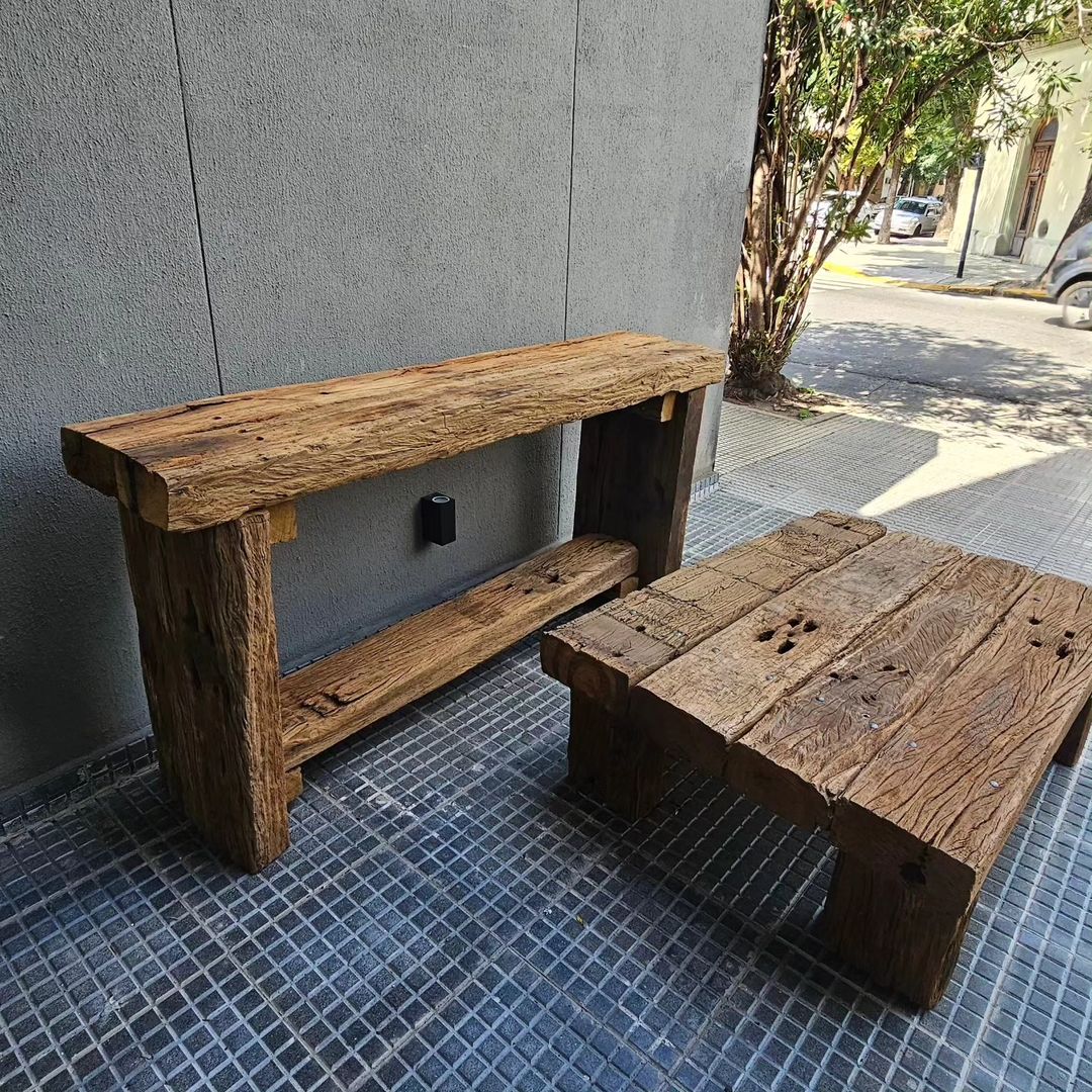 A rustic wooden bench with a textured finish against a modern grey wall.