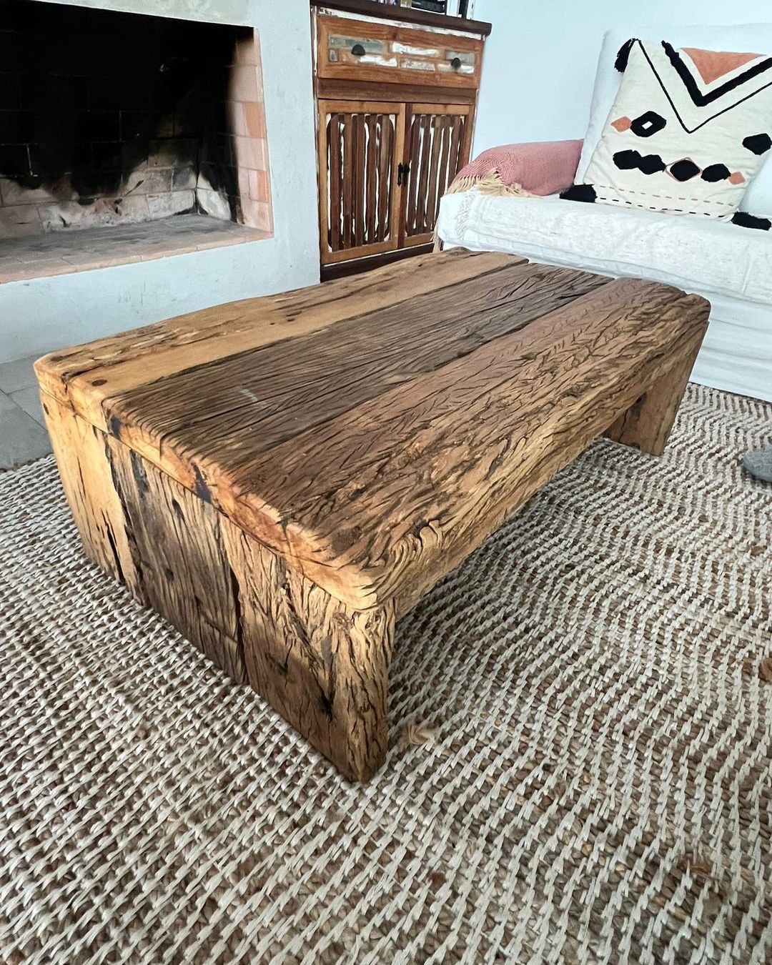 A rustic wooden coffee table with rich textures and robust chunky legs adds a touch of nature-inspired charm to this cozy living room setup.