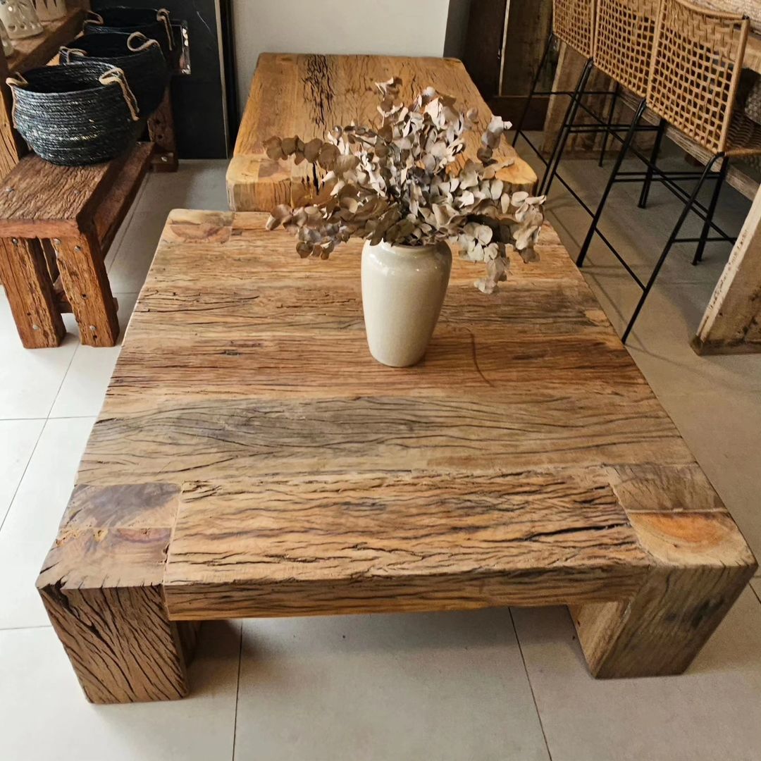 A rustic wooden coffee table with a ceramic vase and dried leaves arrangement