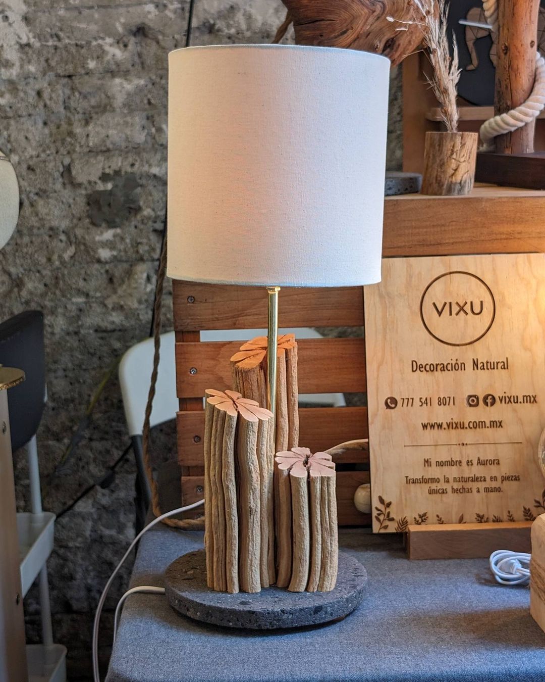 A handcrafted lamp with a rustic design featuring wooden logs and delicate leaf accents