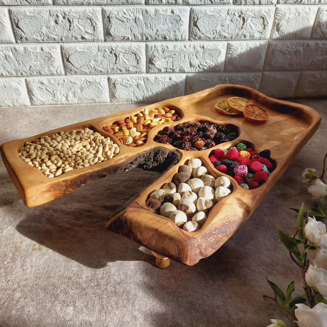 A rustic wooden serving tray displaying an assortment of nuts, dried fruits, and colorful candies