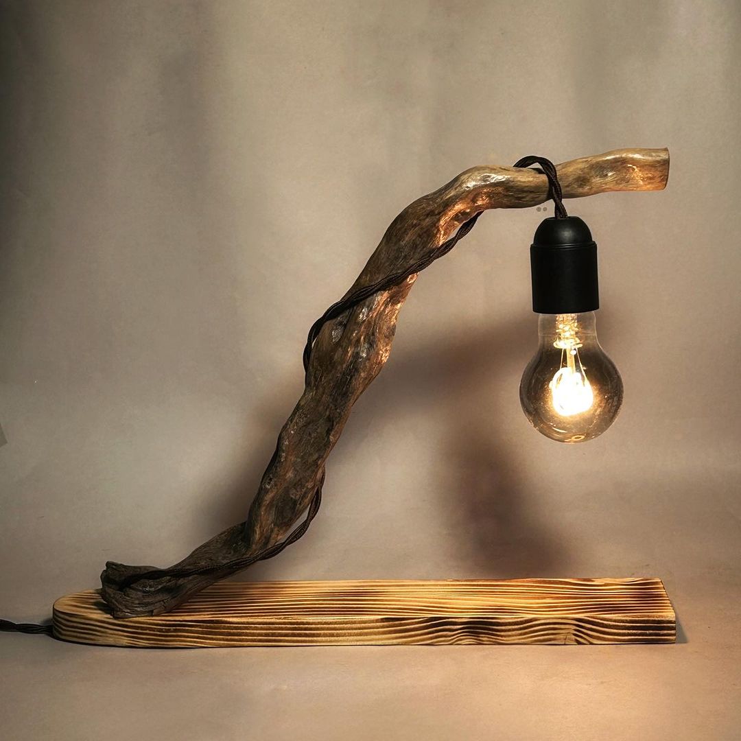 A uniquely crafted wooden lamp with a dangling edison bulb