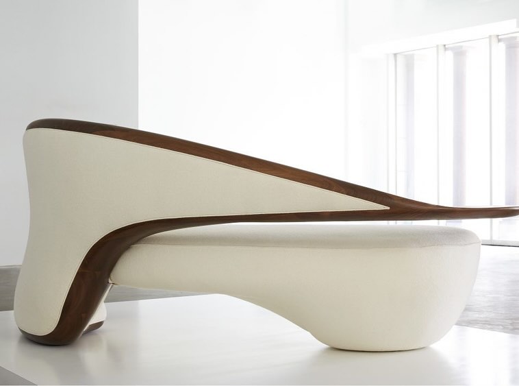 An innovative chaise lounge with a sweeping wooden frame and elegant cream upholstery