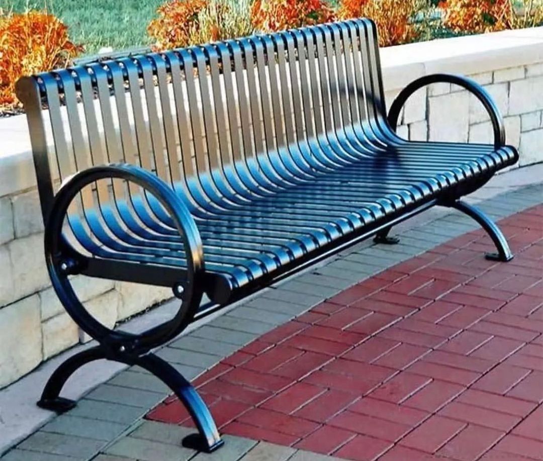 Metal bench with a modern design on a brick pavement.