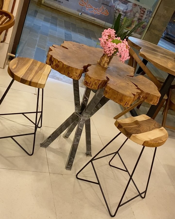 A chic artisanal cafe corner featuring a live-edge wood table paired with modern geometric metal stools.