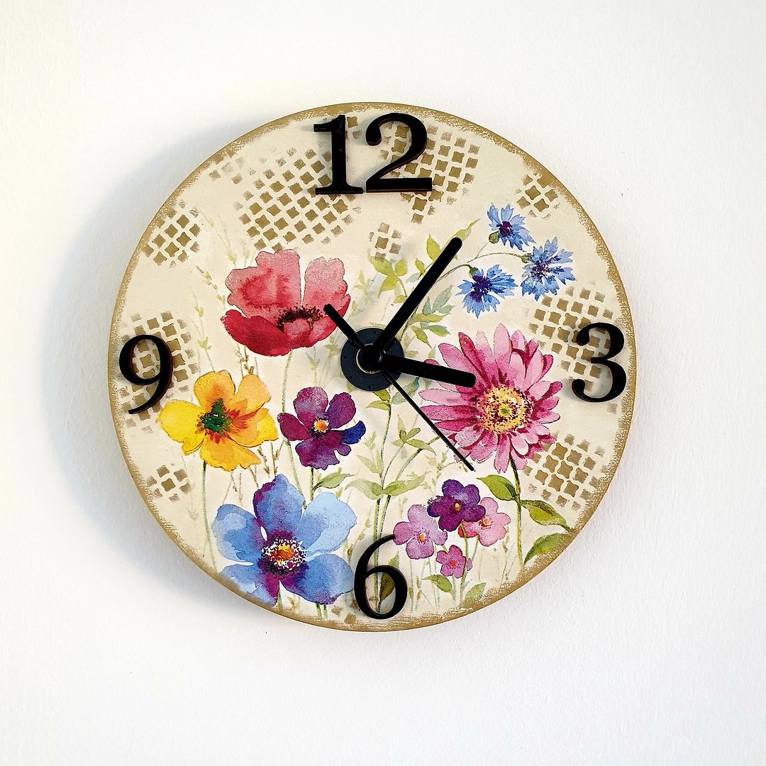 A vibrant wall clock with colorful floral illustrations on an antiqued background