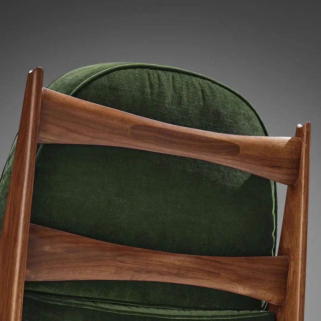 A modern green velvet chair with a wooden frame