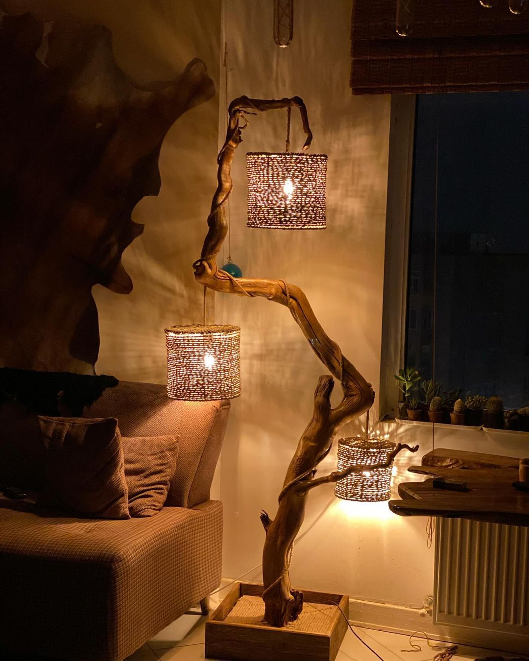 A unique floor lamp crafted from twisted driftwood, with two pendant lights encased in wicker baskets casting a warm glow