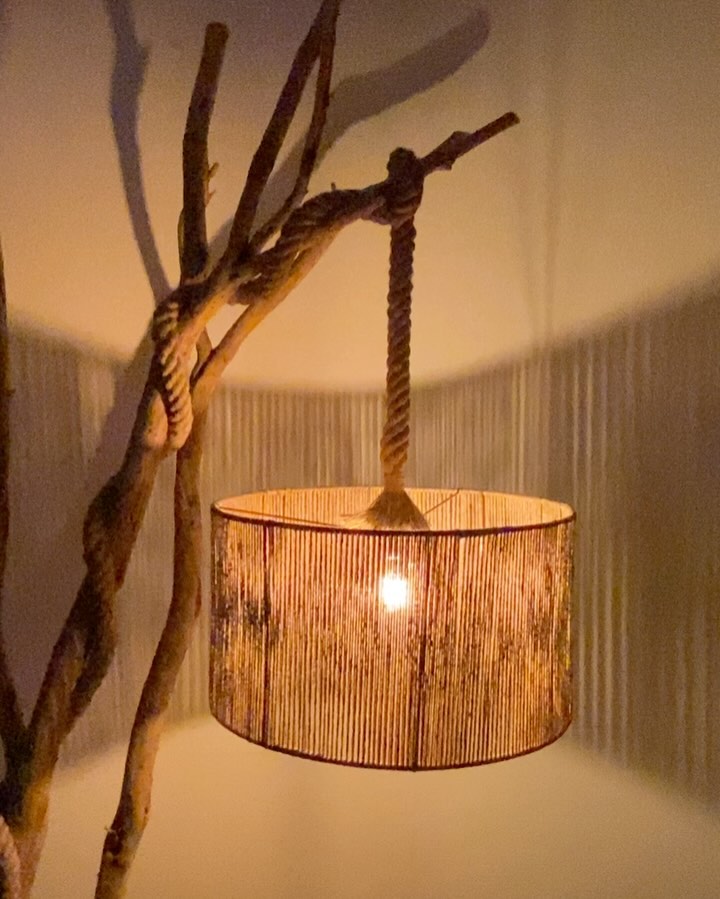 A lamp with a twisted wooden stand casting a gentle glow through a textured cylindrical shade