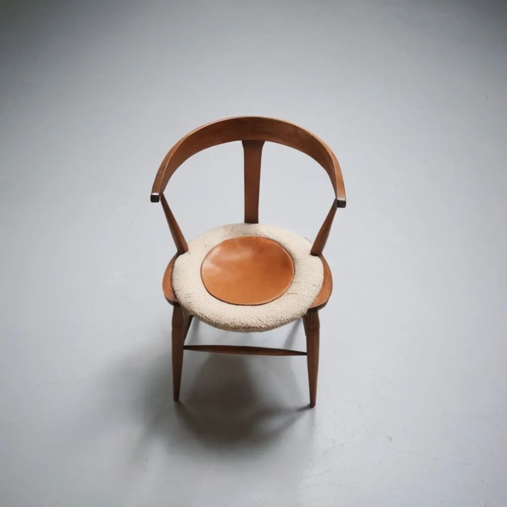 A unique wooden chair with a round leather seat cushion and fluffy ring around it