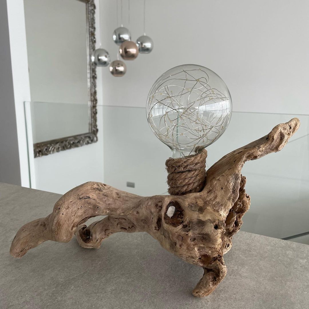 An artistic light fixture created from twisted driftwood and a spherical bulb with a filament design