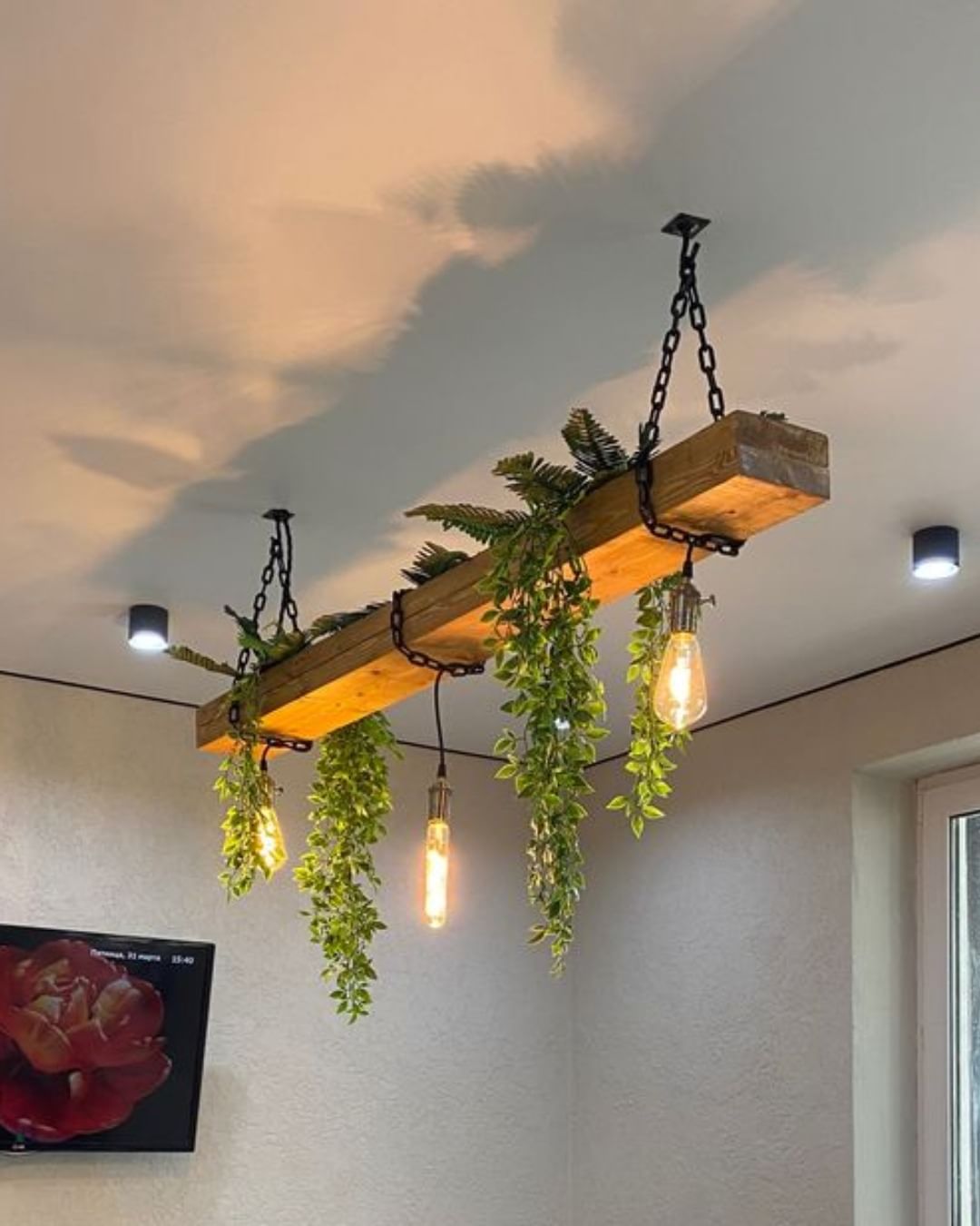 A rustic wood and chain lighting fixture adorned with greenery