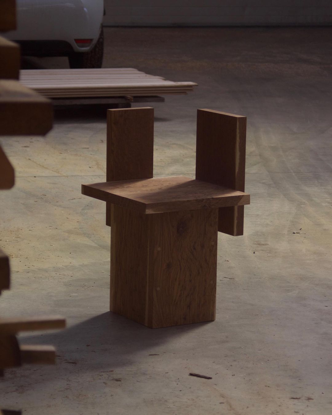 A unique wooden chair featuring a minimalist design with block-like arms and a sturdy base