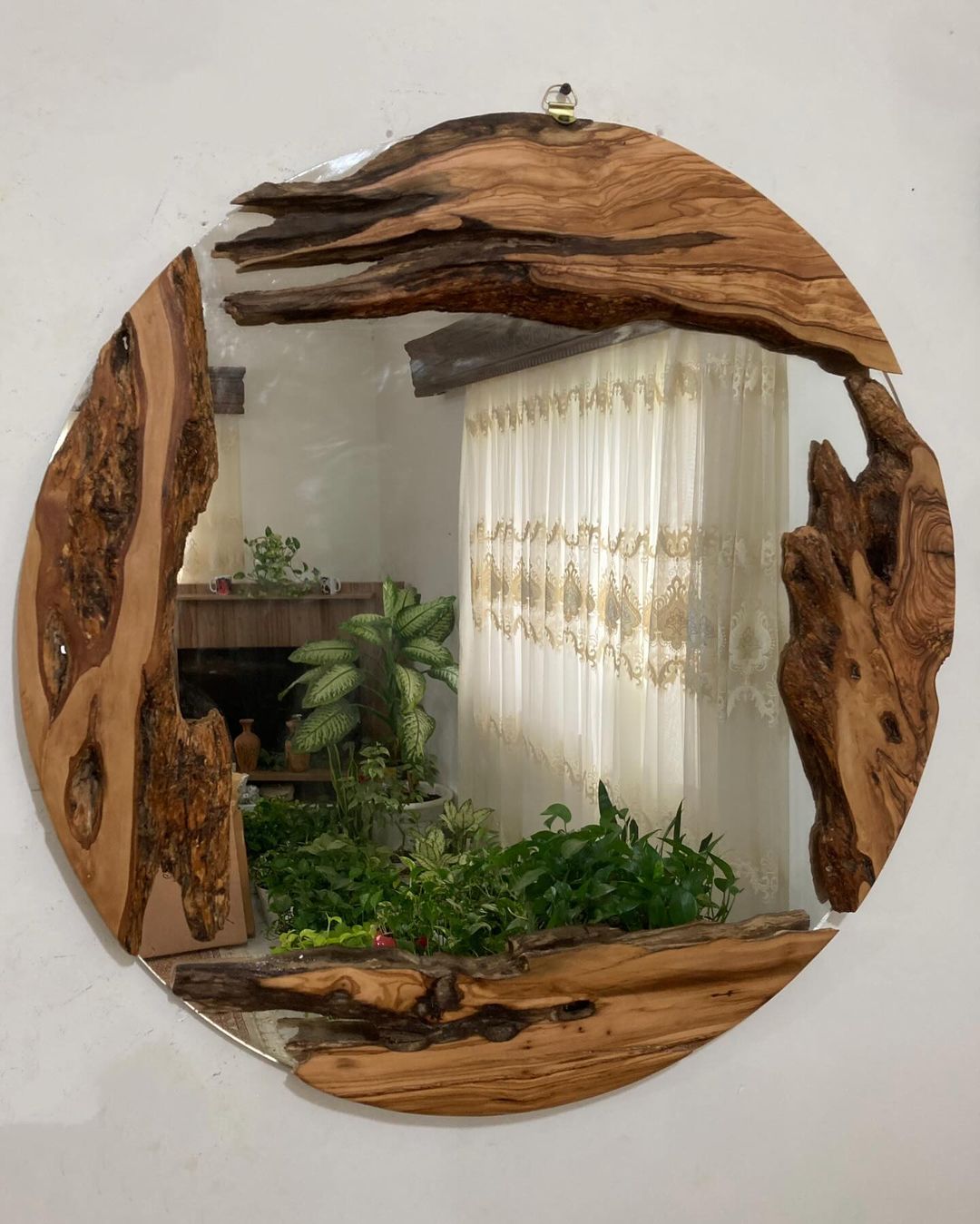 A rustic circular mirror framed with textured natural wood adding warmth to a minimalist room.