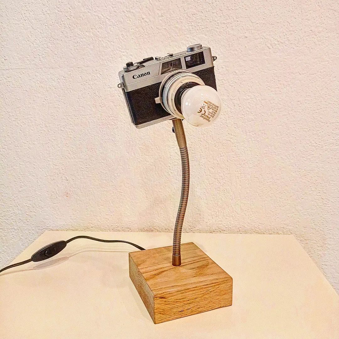 A uniquely crafted lamp with a vintage Canon camera body and an attached light bulb